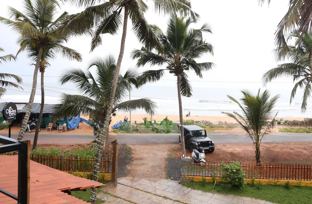 Olam by the Sea — beach view through palm trees, Kerala