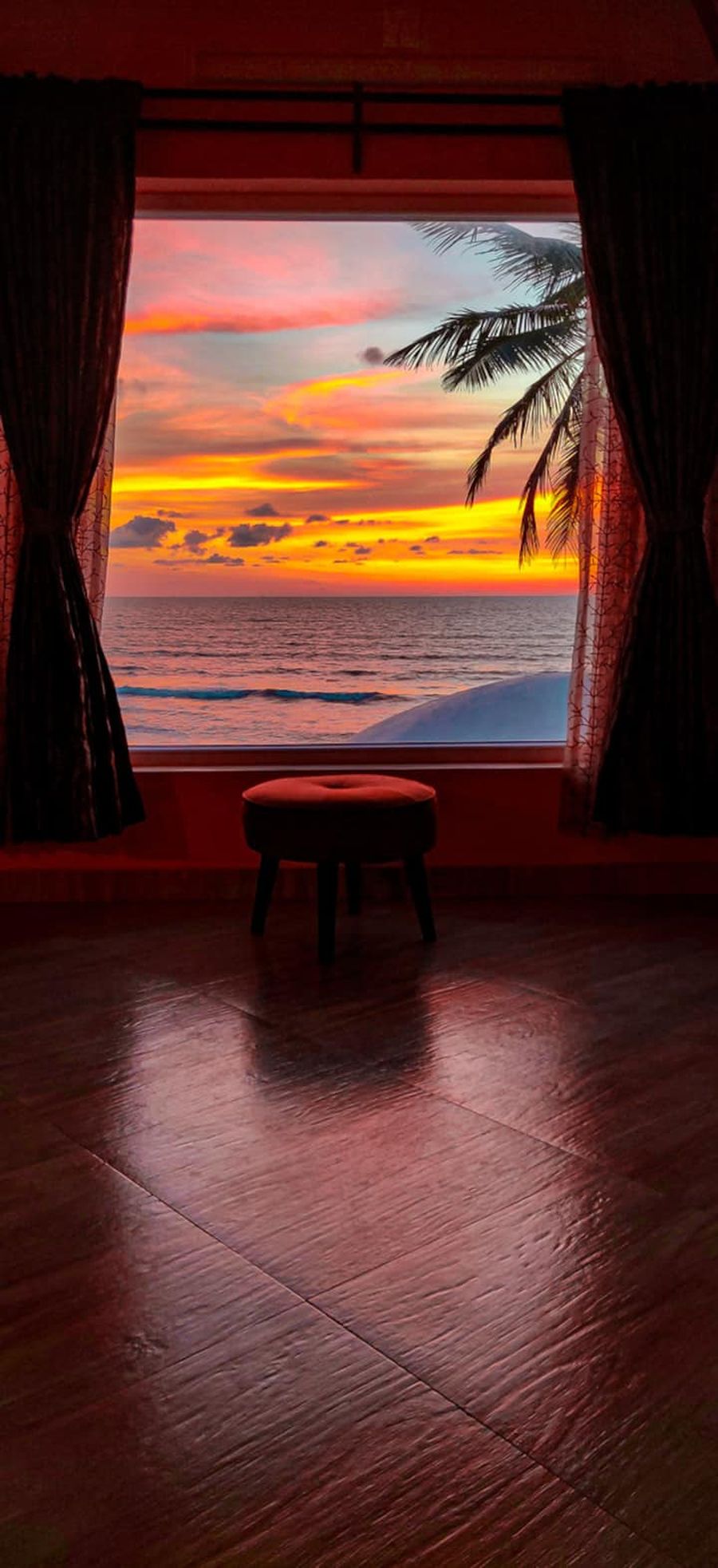 White Noise bedroom window framing a fire sunset over the ocean