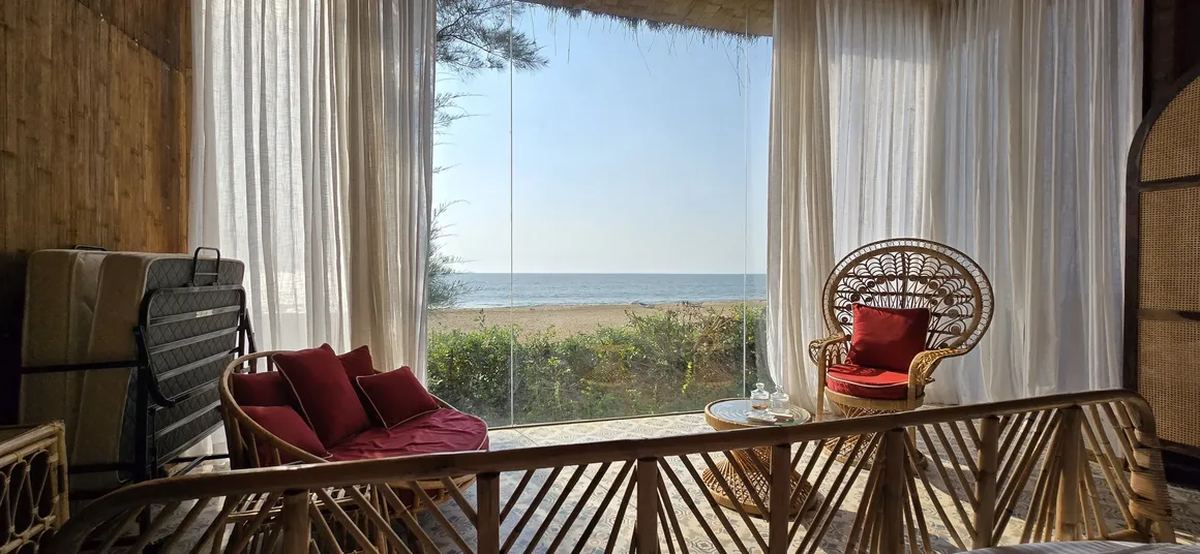 Kurma — peacock rattan chairs with full sea view through glass